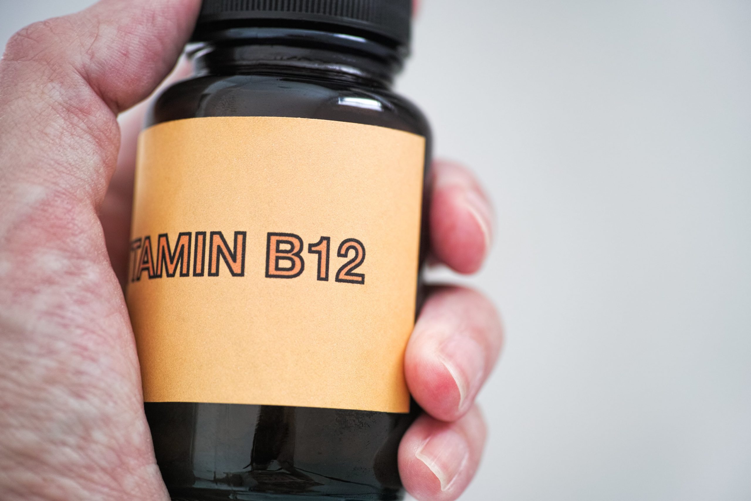 A man holding Vitamin B12 written medicine bottle | The Importance of Vitamin B12 | Hydription in Torrance, CA