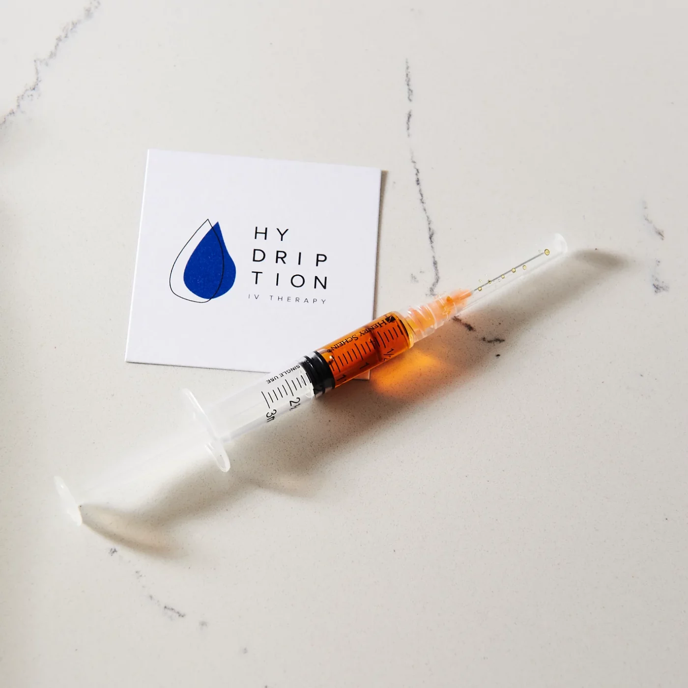 A Syringe with medicine on the floor with the card of Hydription | Best IV Therapy Lounge in Torrance, CA